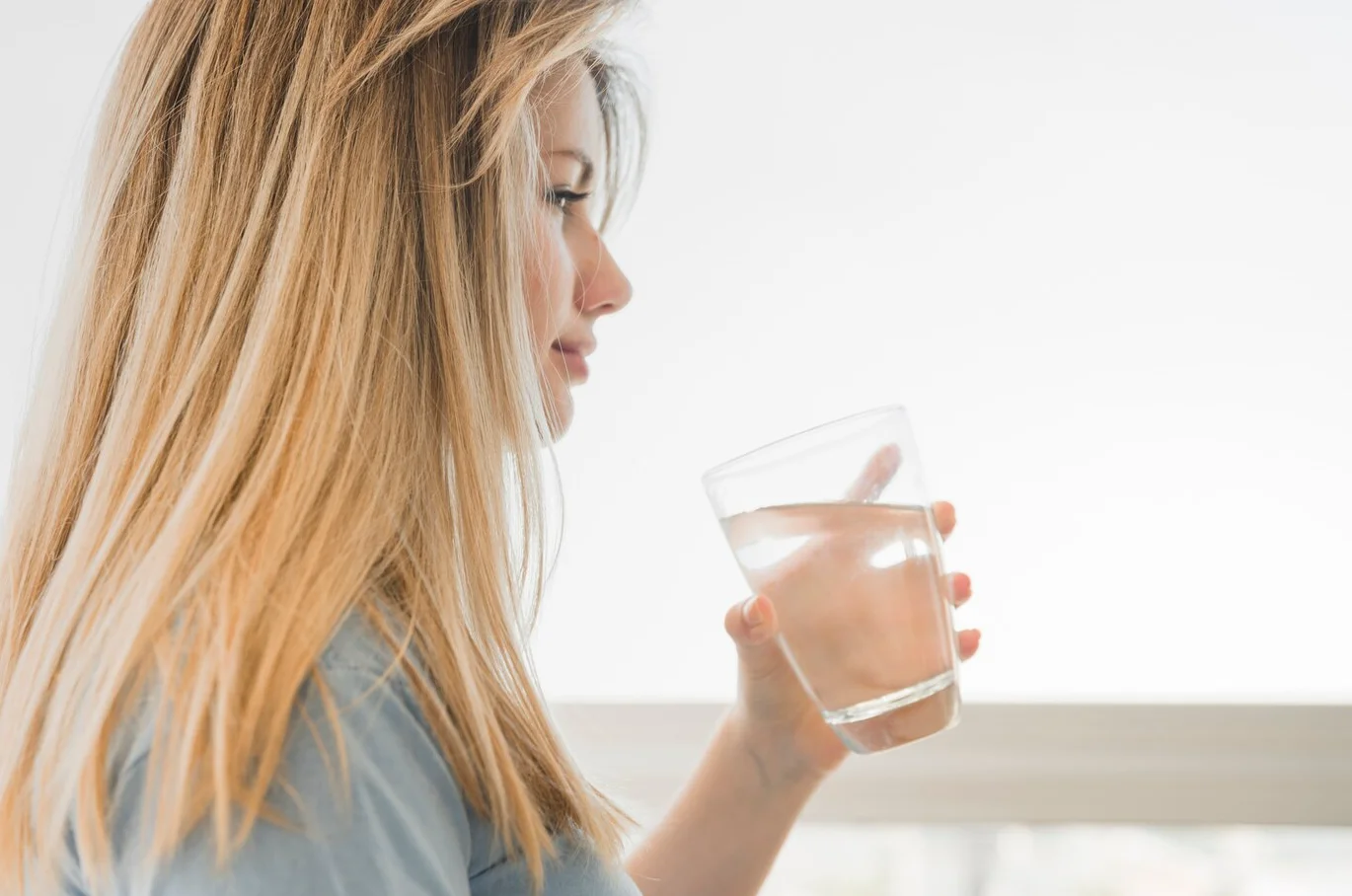 mulher bebendo agua para evitar barriga inchada